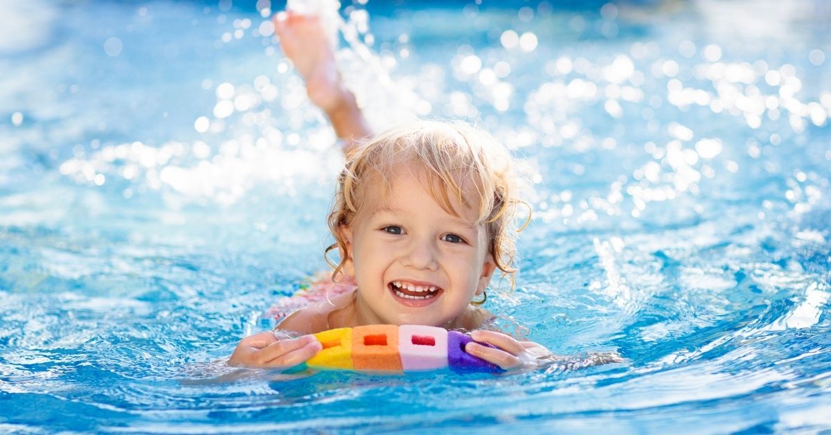 young child swimming in a pool on top of pool noodles