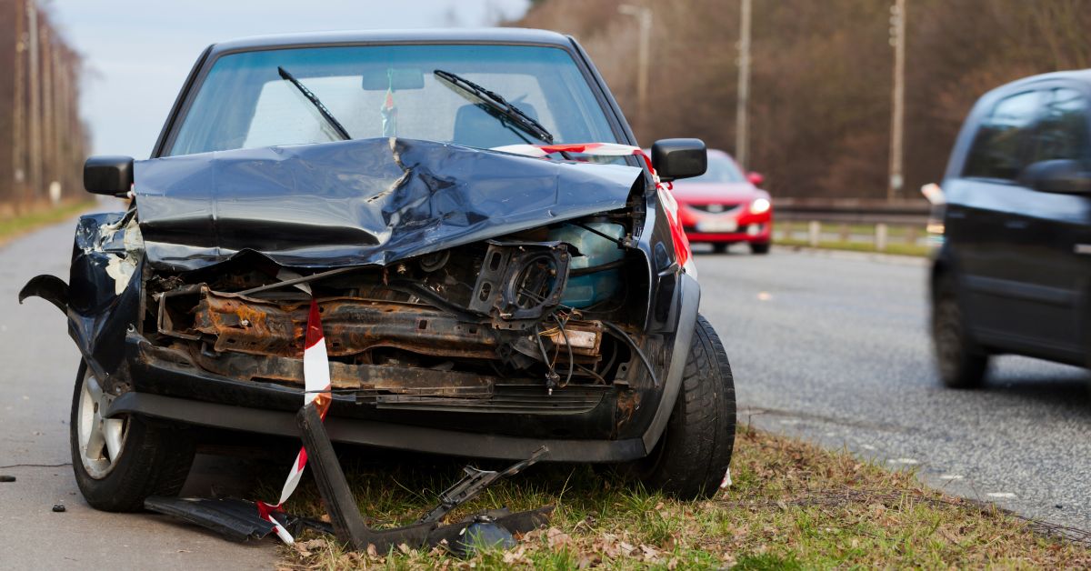 small passenger car on the side of the road with a completely smashed-in front bumper