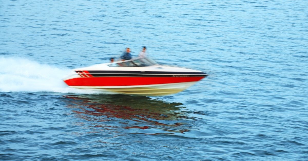 speed boat on a body of water, two blurry people are standing towards the front