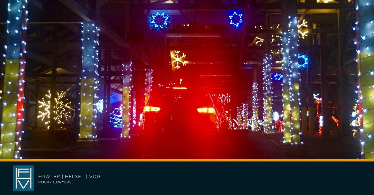 car with brake lights on driving through a holiday light tunnel